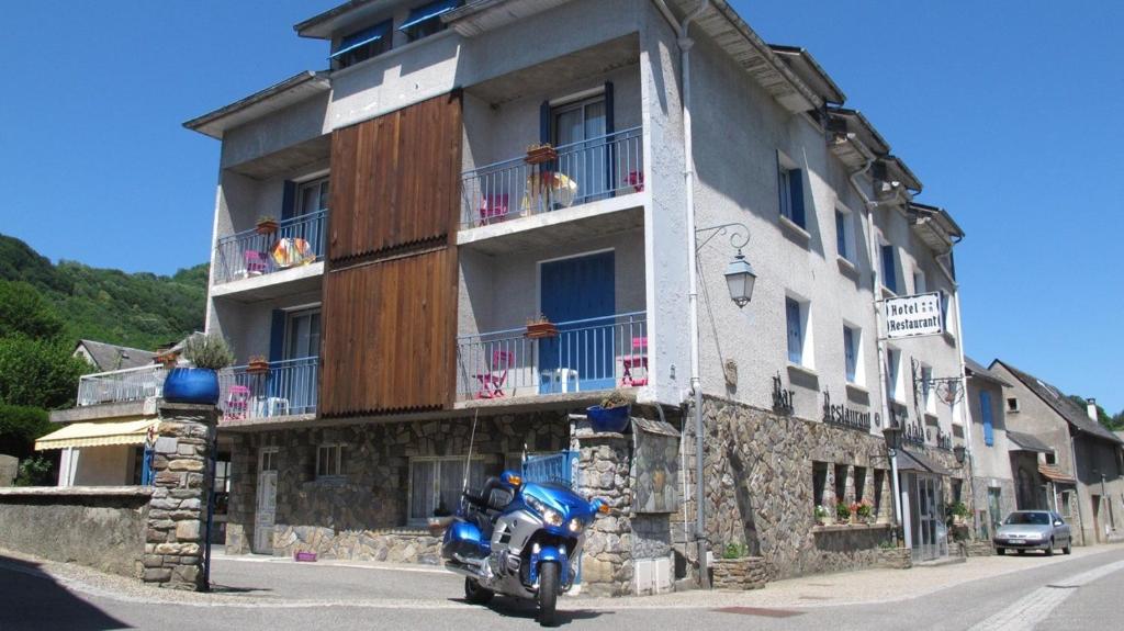 a blue motorcycle parked in front of a building at Hôtel Le Catala in Beaudéan