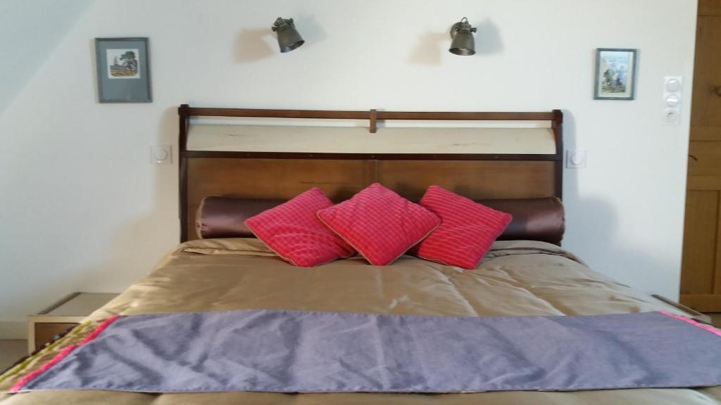 ein Bett mit zwei rosa Kissen darauf in der Unterkunft Manoir de la Ville Marie in Hirel