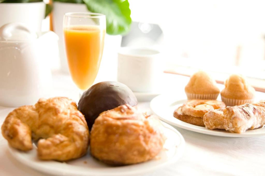 a table with two plates of pastries and a glass of orange juice at Gran Hotel Concordia in Salto