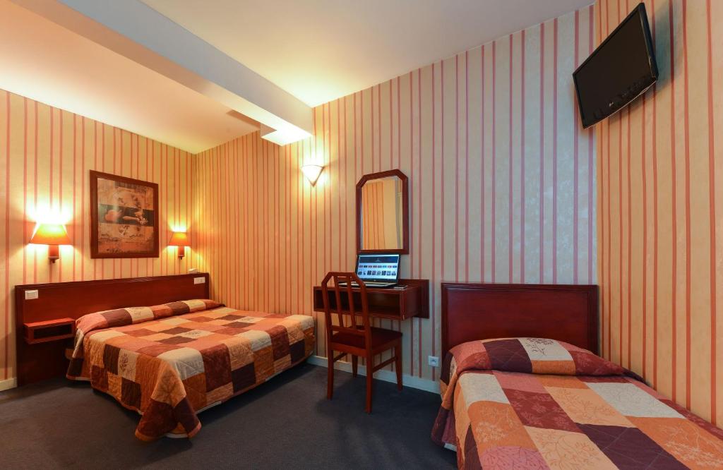 ein Hotelzimmer mit 2 Betten und einem Schreibtisch mit einem Computer in der Unterkunft Maison Du Pré in Paris