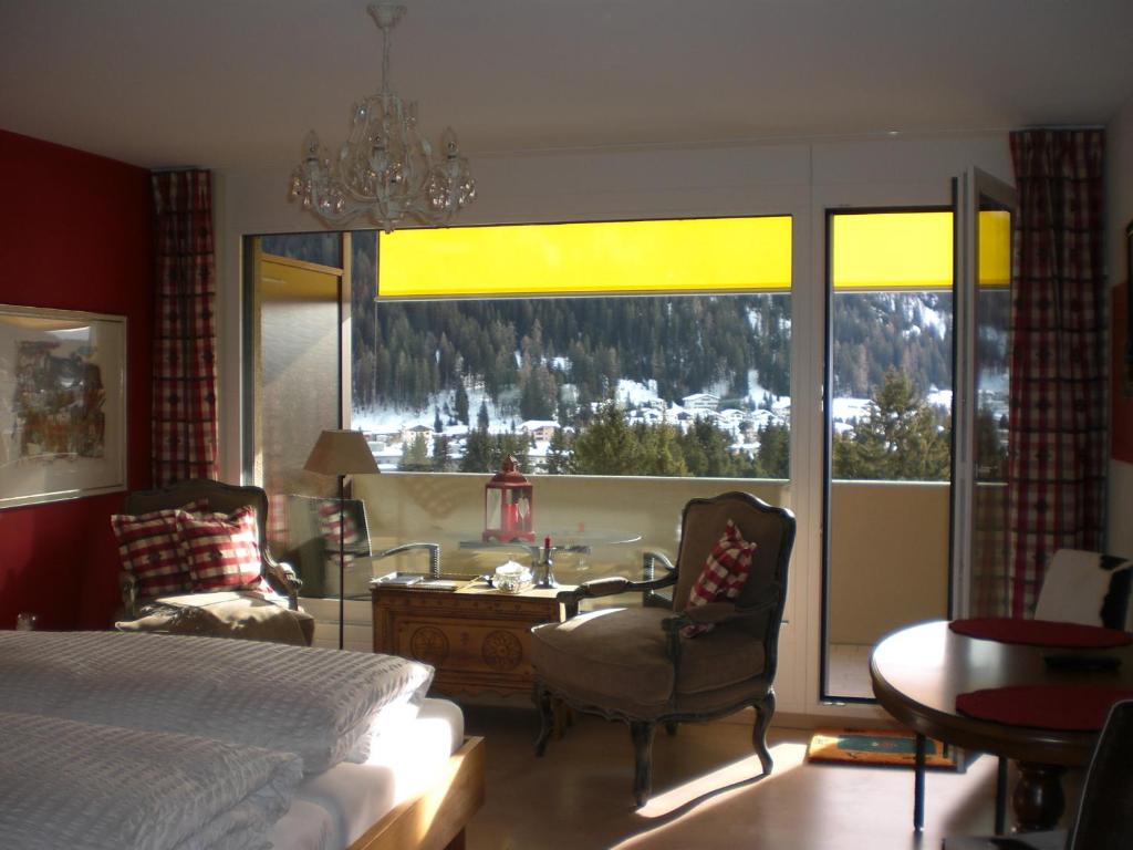 a bedroom with a bed and a large window with a view at Studio Carlton am Park in Davos