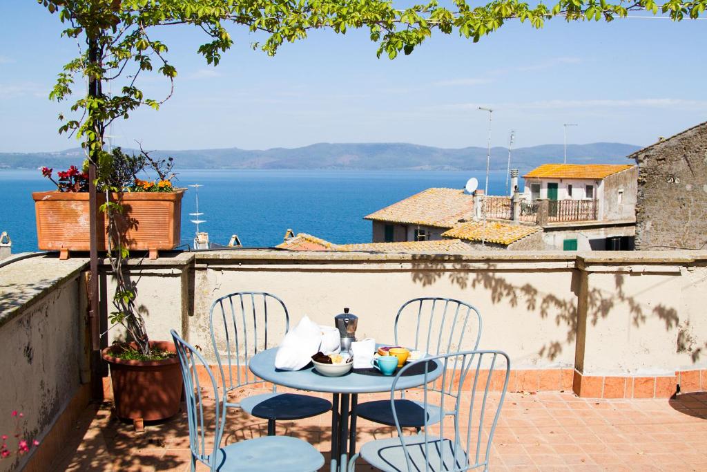 una mesa y sillas en un balcón con vistas al océano en La Dimora di Checchino, en Anguillara Sabazia