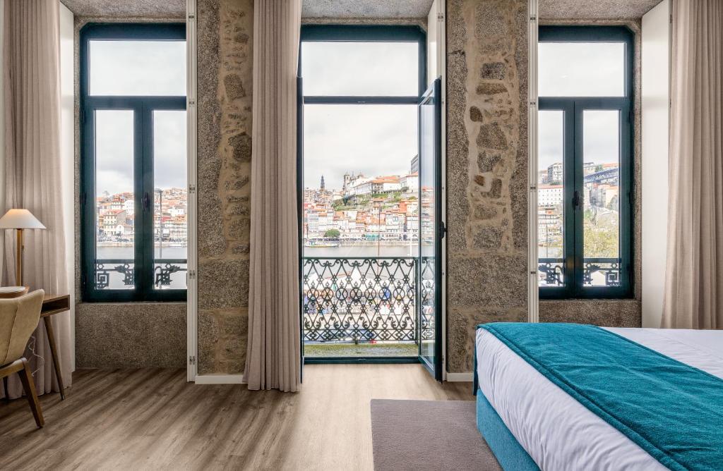 ヴィラ・ノヴァ・デ・ガイアにある296 Heritage Apartmentsのベッドと大きな窓が備わるホテルルームです。