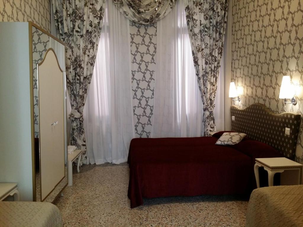 a bedroom with a bed and a window with curtains at Hotel Ca' Nobile Corner in Venice