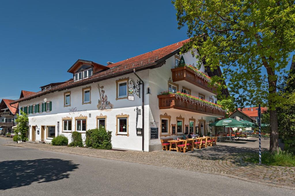 a white building with tables and chairs on a street at Landhotel zum Metzgerwirt in Bad Bayersoien