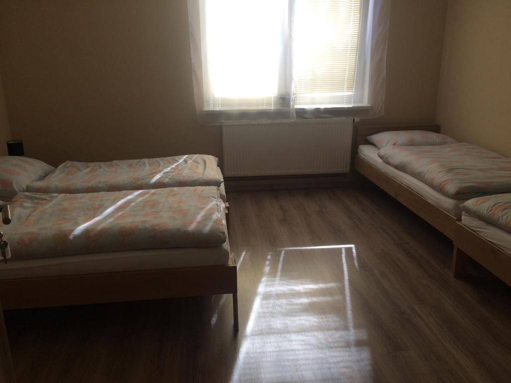 two beds in a room with a window and wooden floors at U Vrbů in Vrbovec
