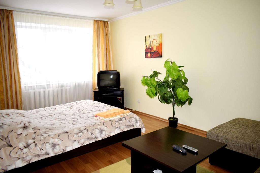 Schlafzimmer mit einem Bett, einem TV und einem Tisch in der Unterkunft Apartment on Krushelnitskoy 73 in Riwne
