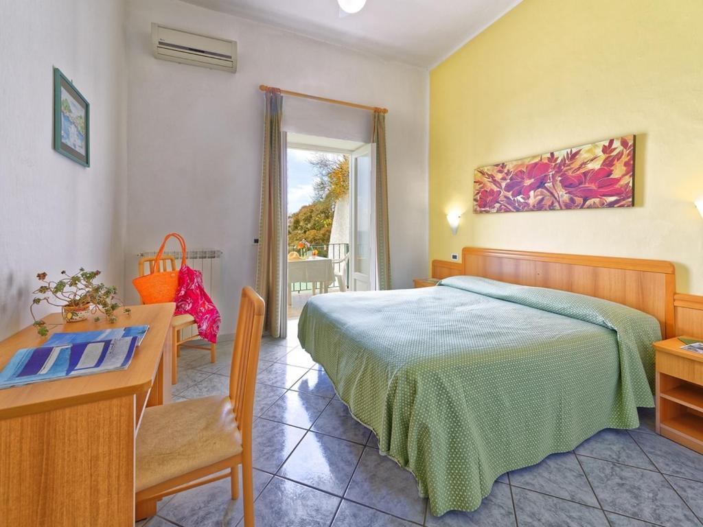 1 dormitorio con cama, mesa y escritorio en Hotel Villa Franz, en Isquia