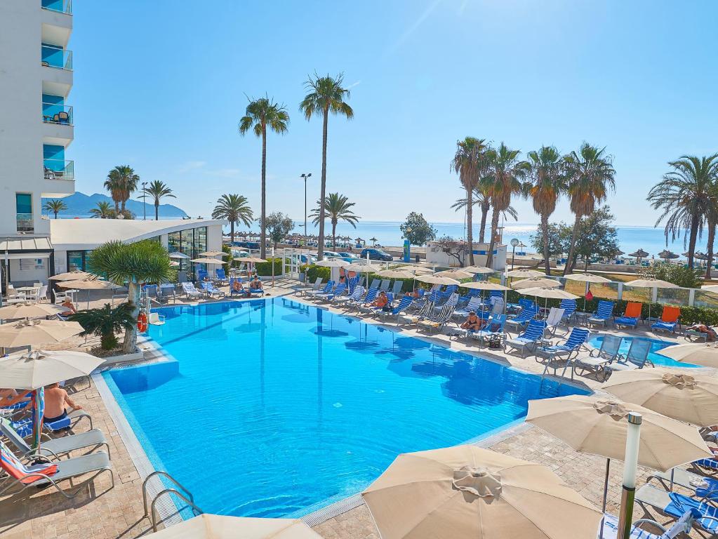 una grande piscina con sedie e ombrelloni di Hipotels Hipocampo - Adults Only a Cala Millor