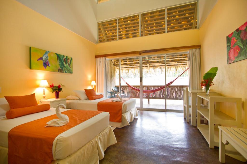 ein Schlafzimmer mit 2 Betten und ein Zimmer mit einem Vogel darauf in der Unterkunft Villas del Caribe in Puerto Viejo