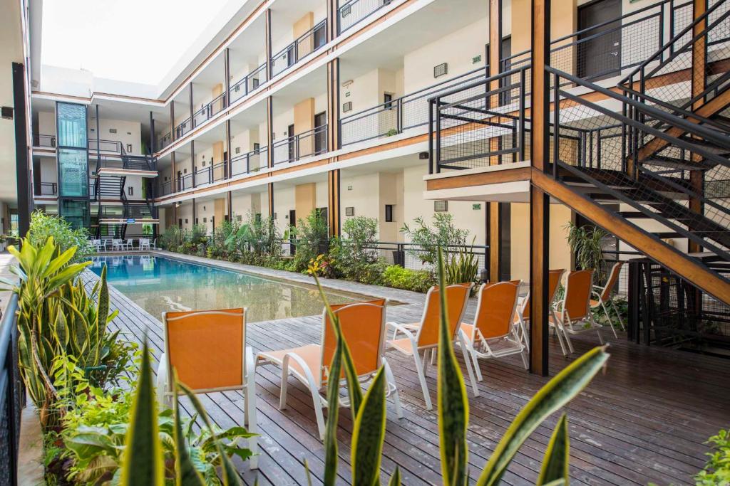 een appartementencomplex met een zwembad en oranje stoelen bij Hotel Andiroba Palace in Tuxtla Gutiérrez