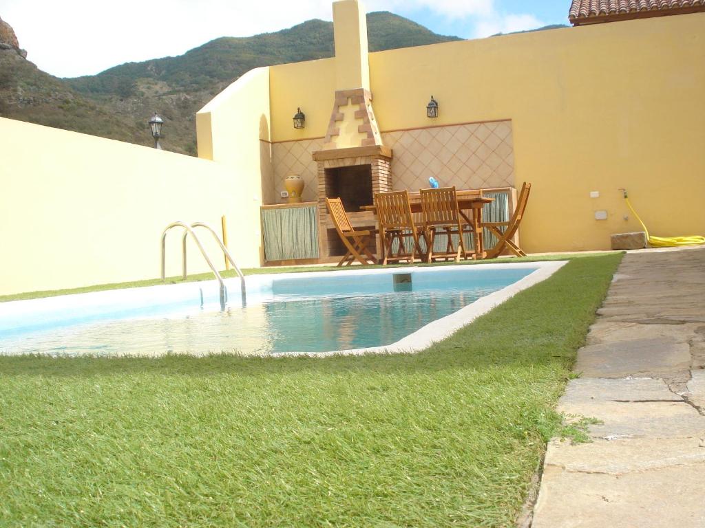 een huis met een zwembad met een tafel en een open haard bij Villa Las Salineras in Buenavista del Norte