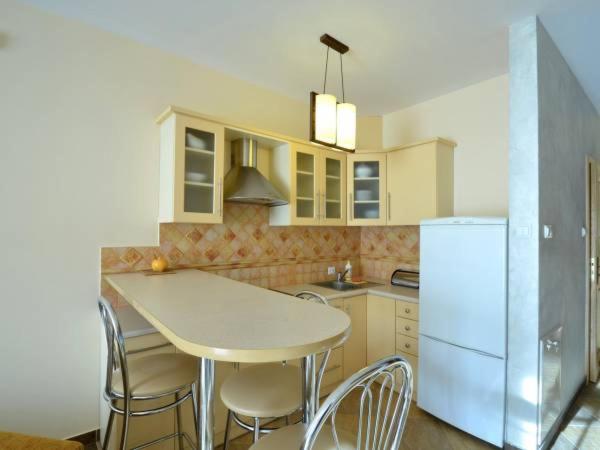 uma cozinha com uma mesa e cadeiras e um frigorífico em Apartamenty i Pokoje "U BARBARY" em Ełk