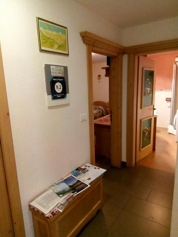Pokój z łóżkiem i stołem z zegarem na ścianie w obiekcie B&B Il Tulipano w mieście San Pietro di Cadore