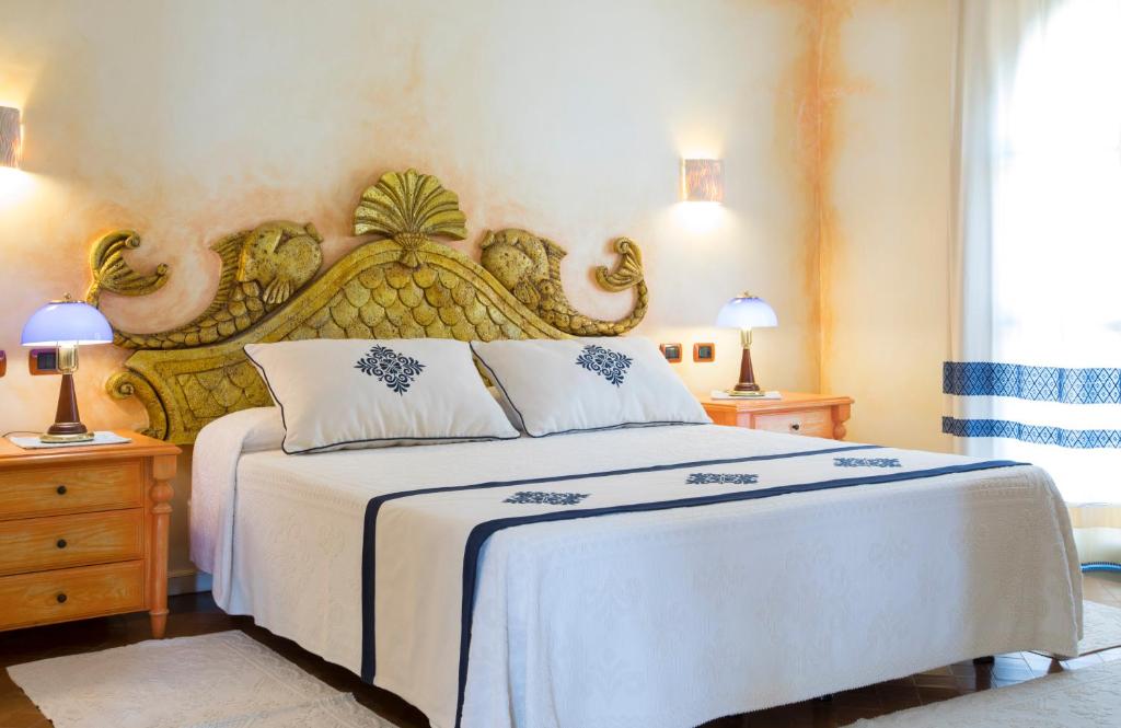 a bedroom with a large bed with a large headboard at Hotel Poseidonia in Àrbatax