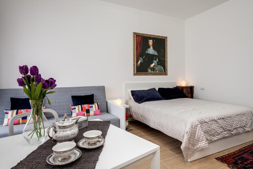 ein Schlafzimmer mit einem Bett und einem Tisch mit lila Blumen in der Unterkunft Dreamsrome Lux in Rom