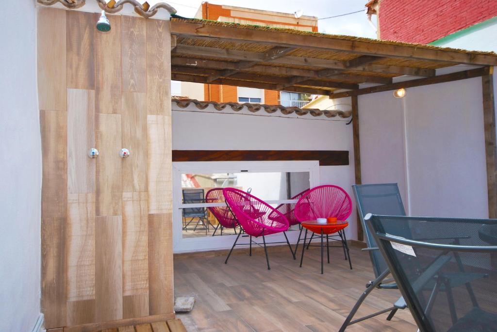 um pátio com cadeiras cor-de-rosa e uma pérgola de madeira em Apartments Valencia, Cabañal em Valência