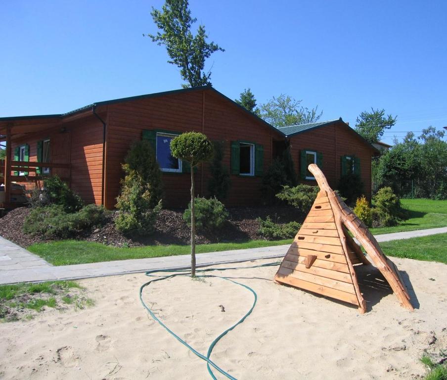 a wooden play structure in the sand in front of a house at Róża Wiatrów - domki Jastrzębia Góra in Jastrzębia Góra