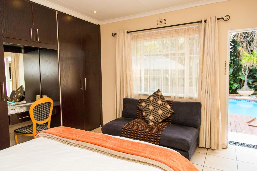 a bedroom with a bed and a chair and a window at Sollunaa Guesthouse in Johannesburg