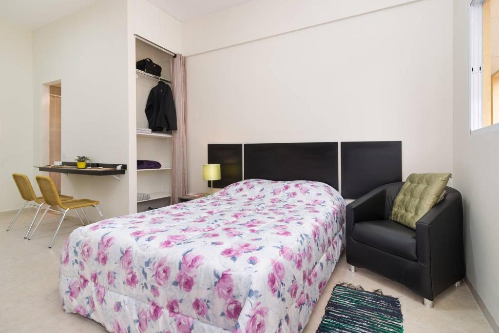 um quarto com uma cama grande e uma cadeira em Studio Ana Laura em São Paulo