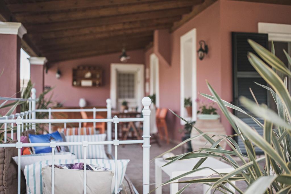 a porch with white chairs and a pink house at Birdsing Cottage in Dassia