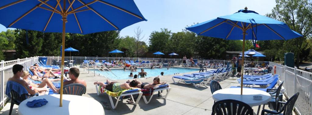 a pool with people sitting in lawn chairs and umbrellas at Island Club Rentals in Put-in-Bay