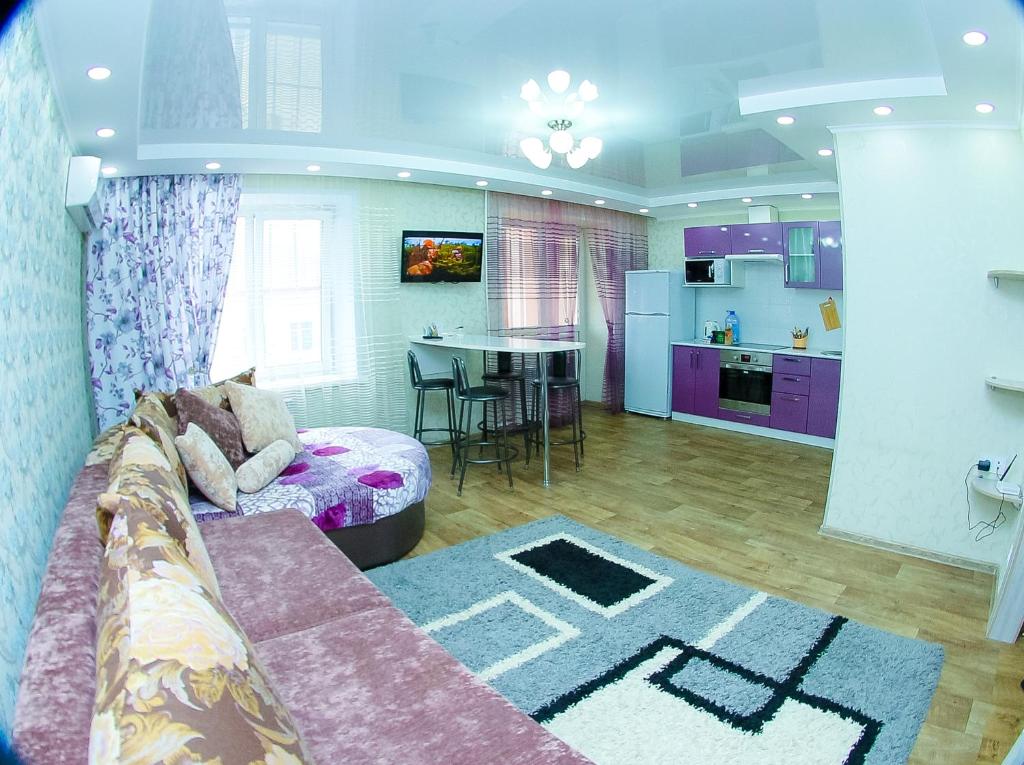 ein Wohnzimmer mit einem Sofa und einer Küche in der Unterkunft ApartLux on Republic Square in Öskemen