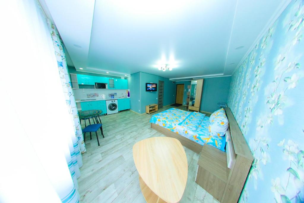 ウスチ・カメノゴルスクにあるApart Auezov street City Centrの青い壁のベッドルーム1室、ベッド1台、テーブルが備わります。