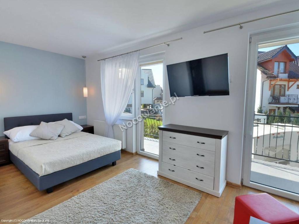 a bedroom with a bed and a flat screen tv at Sztorm in Jastarnia