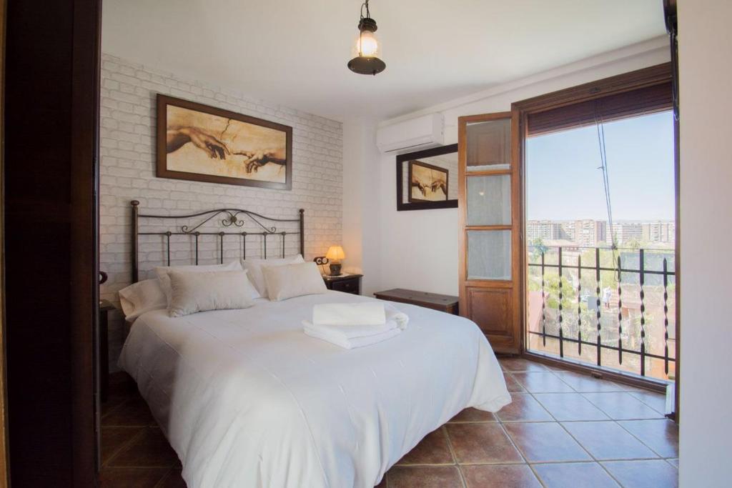 1 dormitorio con cama blanca y balcón en Casita del Realejo, en Granada