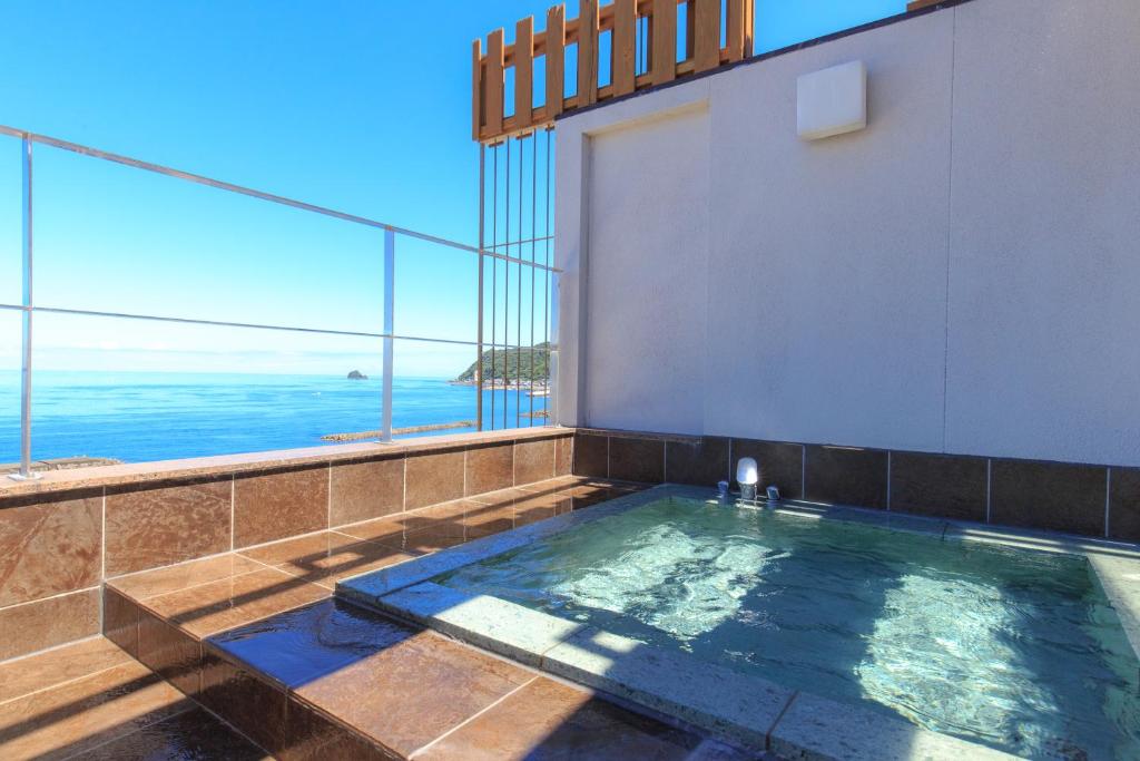 a hot tub with a view of the ocean at Kameya Rakan in Ito