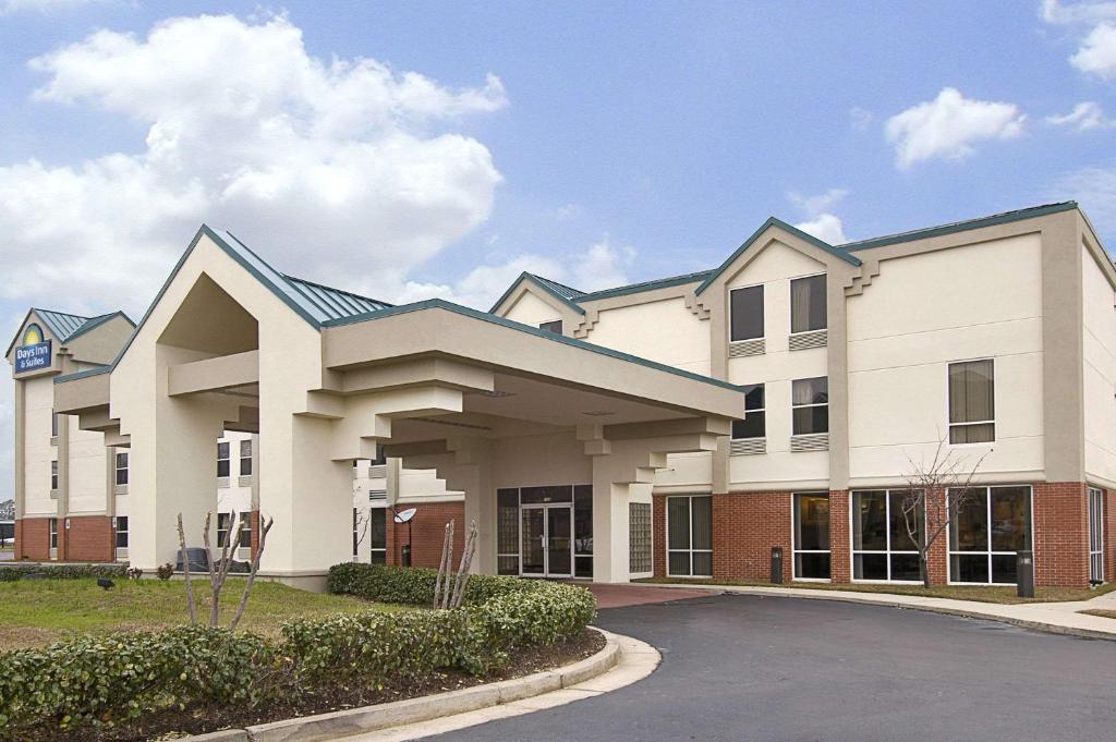 a large white building with a parking lot at Days Inn & Suites by Wyndham Ridgeland in Ridgeland