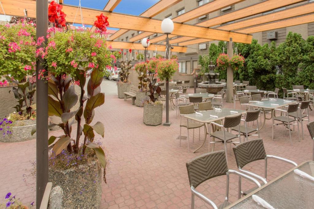 patio ze stołami, krzesłami i kwiatami w obiekcie Ramada by Wyndham Kelowna Hotel & Conference Center w mieście Kelowna