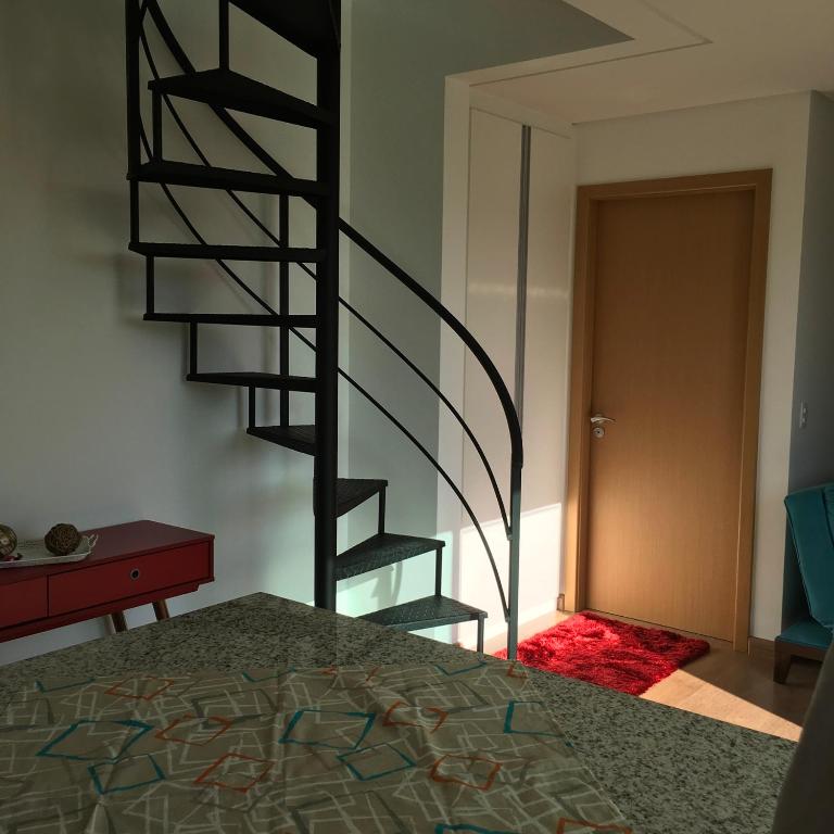 a spiral staircase in a room with a bedroom at Cobertura Aischa Hum in São Paulo