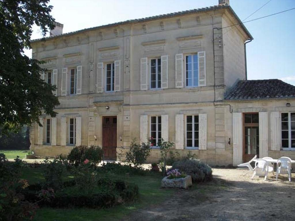 a large stone house with two white chairs in front of it at La Maison des Aurélines in Puisseguin