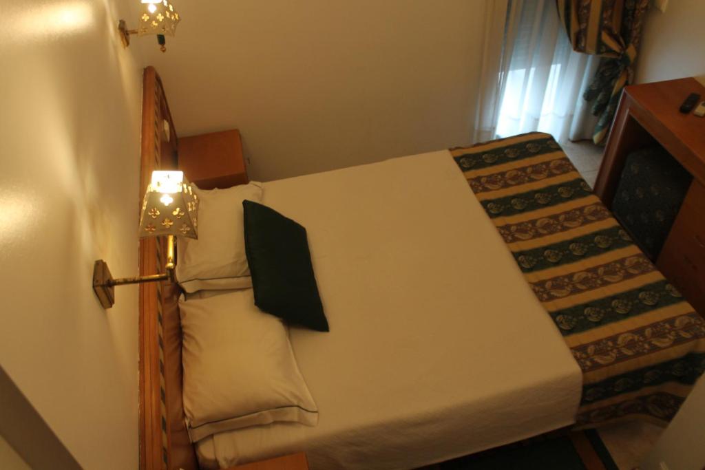 a small bedroom with a bed with a lamp on it at Real Caparica Hotel in Costa da Caparica