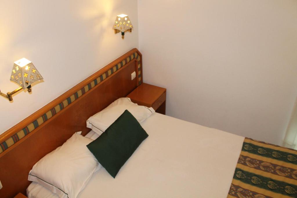 a bedroom with a bed with a green pillow on it at Real Caparica Hotel in Costa da Caparica