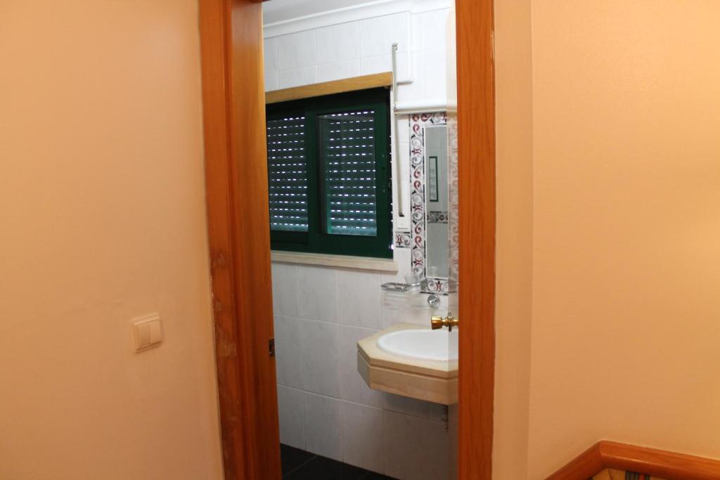 a bathroom with a sink and a mirror at Real Caparica Hotel in Costa da Caparica