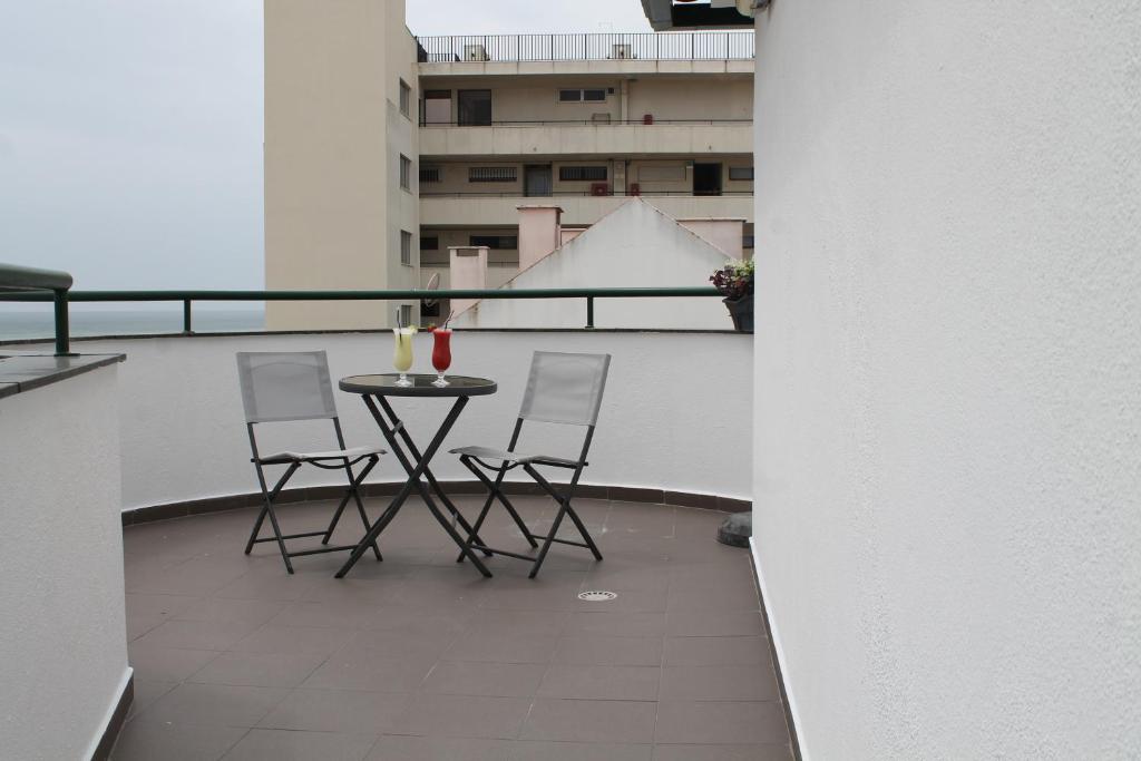 a balcony with a table and chairs on a building at Real Caparica Hotel in Costa da Caparica