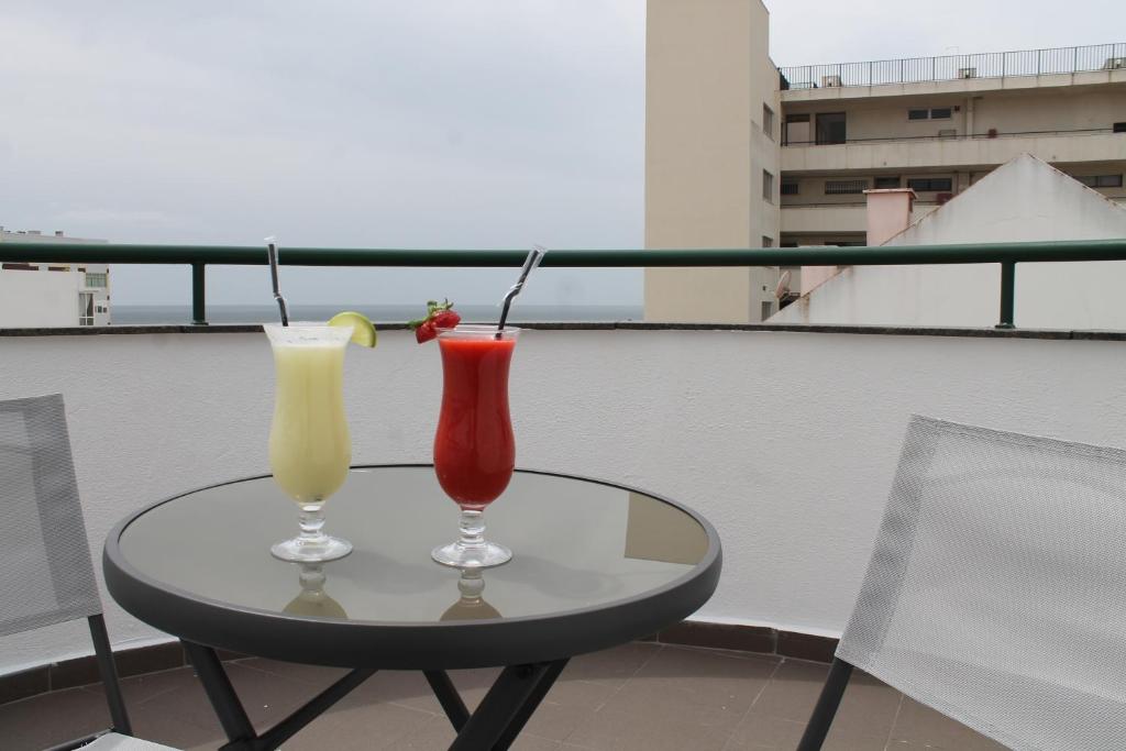 two cocktails sitting on a table on a balcony at Real Caparica Hotel in Costa da Caparica
