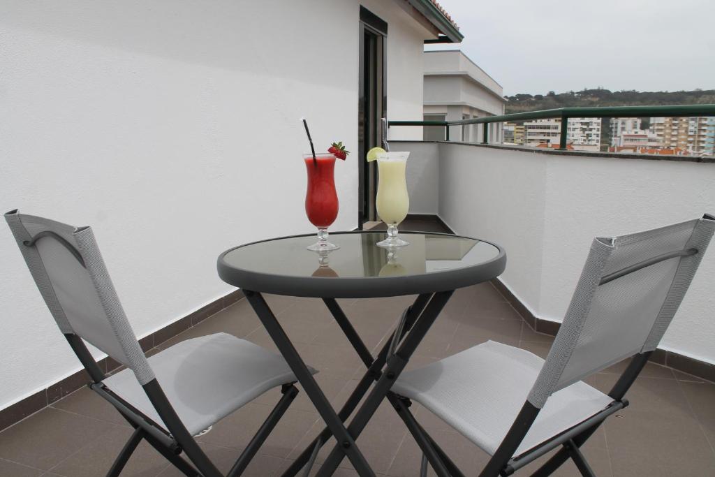 a small table with two drinks on a balcony at Real Caparica Hotel in Costa da Caparica