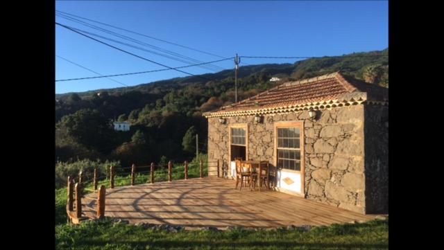Cette petite maison en pierre dispose d'une terrasse avec une table et des chaises. dans l'établissement Casa Deco, La Galga, La Palma, à La Galga