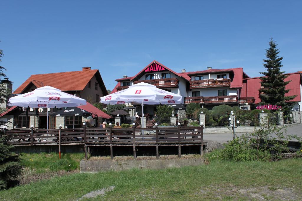 ein Restaurant mit Sonnenschirmen vor einem Gebäude in der Unterkunft Pensjonat MALWA in Brenna