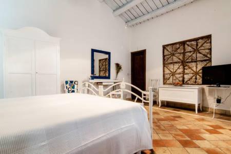una camera da letto bianca con un letto e una TV di A 50 passi dal Tempio di Apollo a Siracusa
