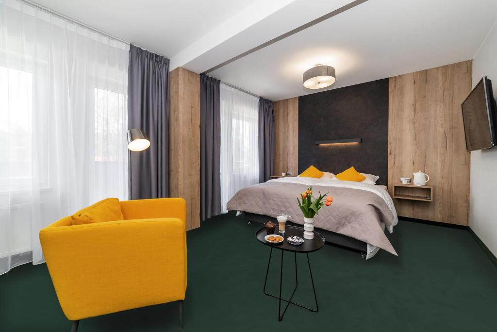 a hotel room with a bed and a yellow chair at Apartamenty PORTO in Giżycko