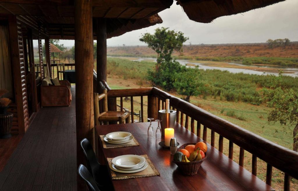 a table on a balcony with a view of a river at Elephant Walk Retreat in Komatipoort