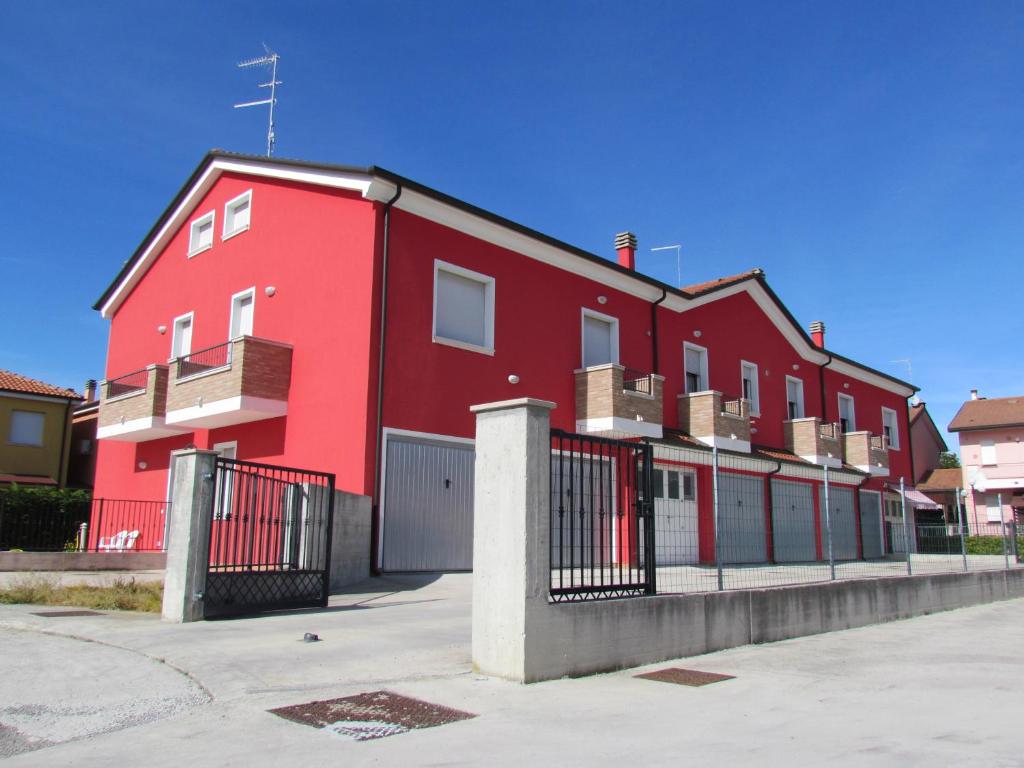 un edificio rojo con una valla delante en Siviero Apartments, en Scardovari