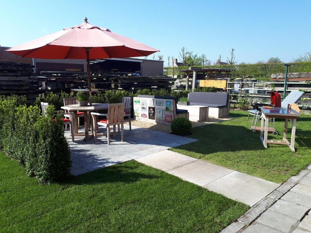 a patio with a table and an umbrella at De Perelaar in Jabbeke