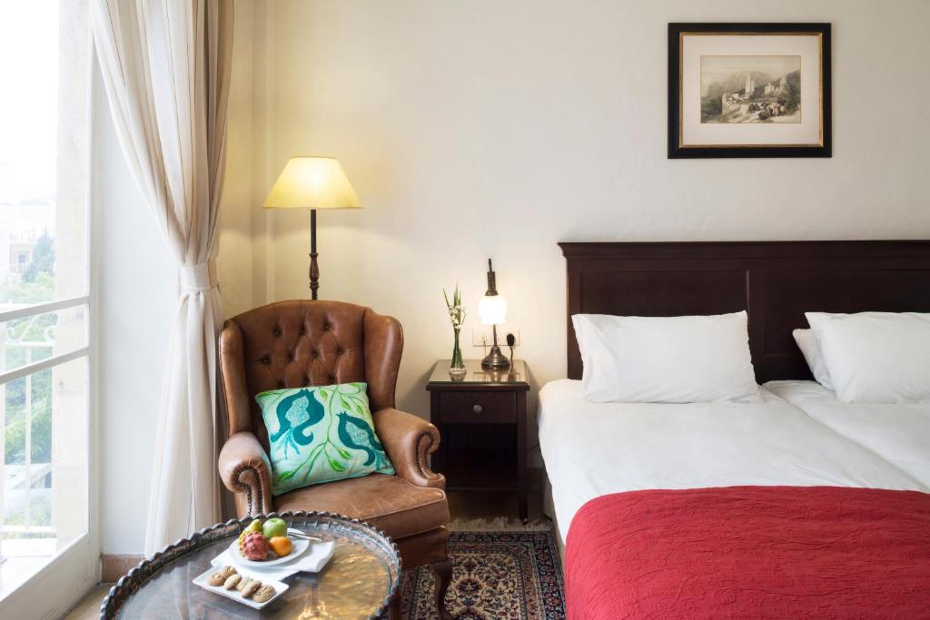 a hotel room with a bed and a chair with a bowl of fruit at The American Colony Hotel - Small Luxury Hotels of the World in Jerusalem