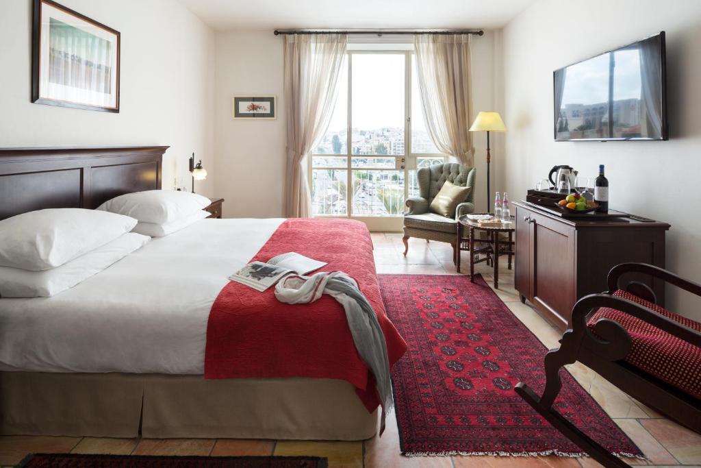 a hotel room with a large bed with a red rug at The American Colony Hotel - Small Luxury Hotels of the World in Jerusalem